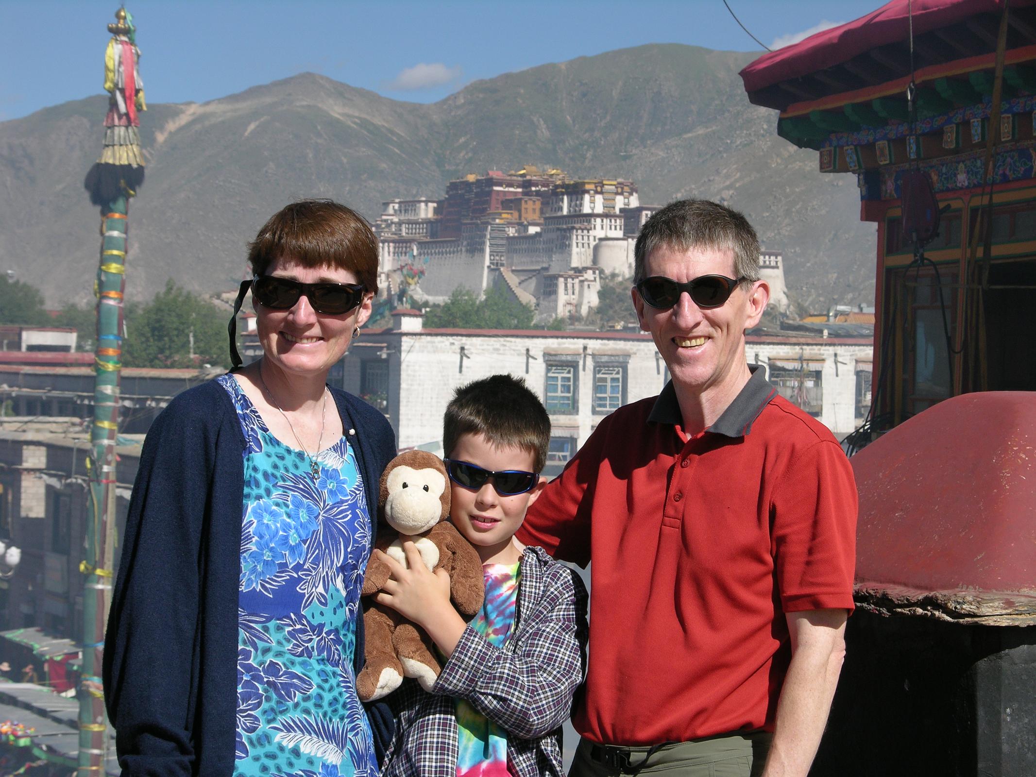 Tibet Lhasa 02 13 Charlotte Ryan, Dangles, Peter Ryan, Jerome Ryan On Jokhang Roof with Potala Behind Charlotte Ryan, Dangles, Peter Ryan, and Jerome Ryan on Jokhang roof with the Potala Palace behind.